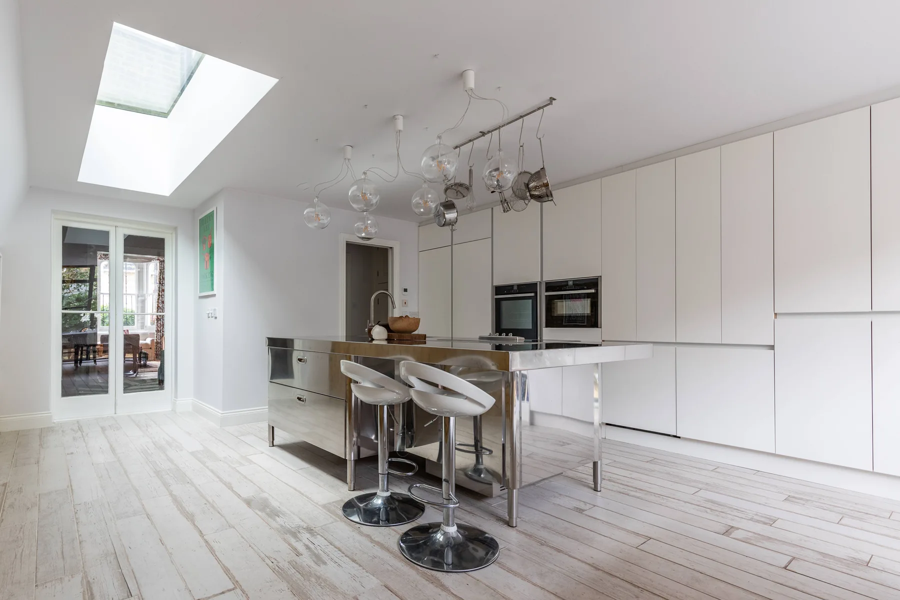 Una cocina moderna y luminosa con una isla central y gabinetes blancos.