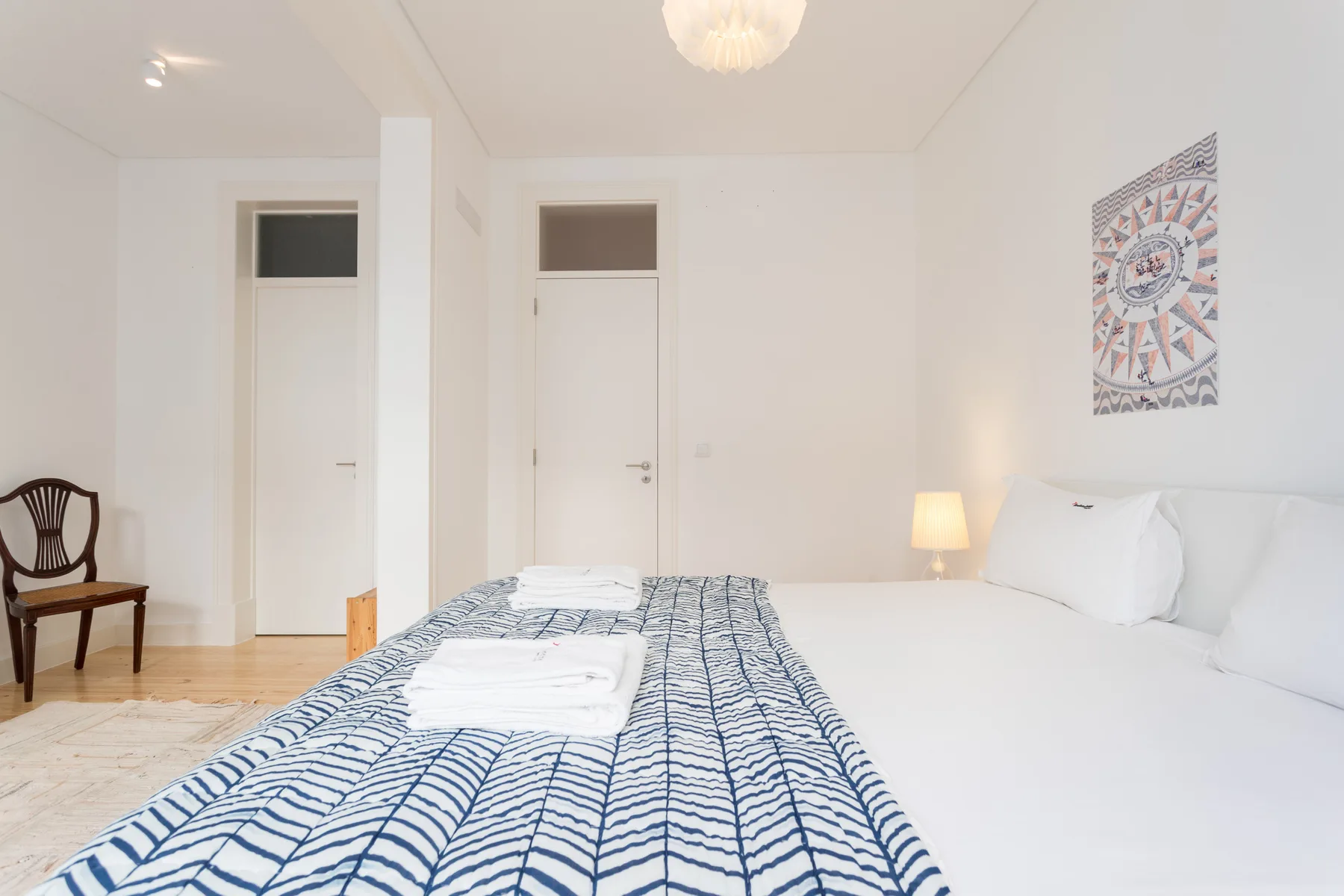 Un dormitorio luminoso con una cama tendida y ropa de cama azul estampada.