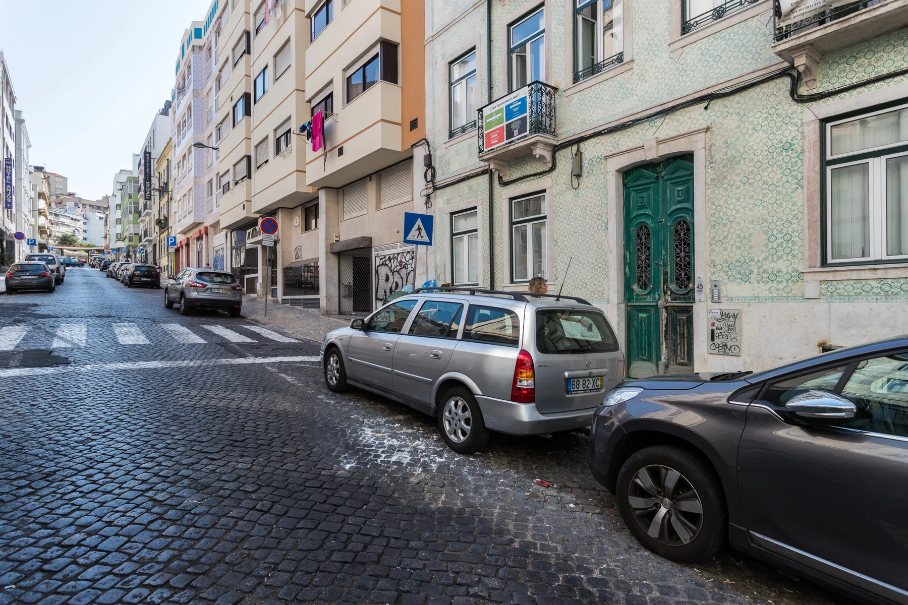 Una calle adoquinada bordeada de edificios de apartamentos y coches aparcados.