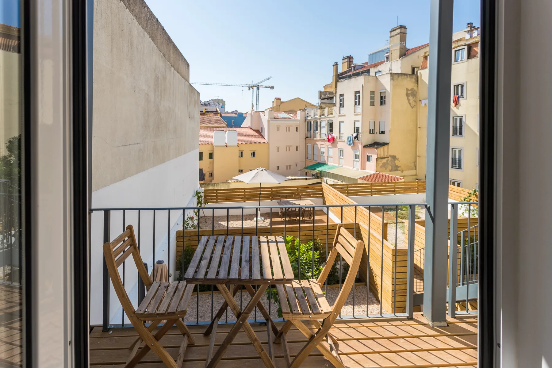 Un balcón con asientos de madera da a edificios cercanos de la ciudad.
