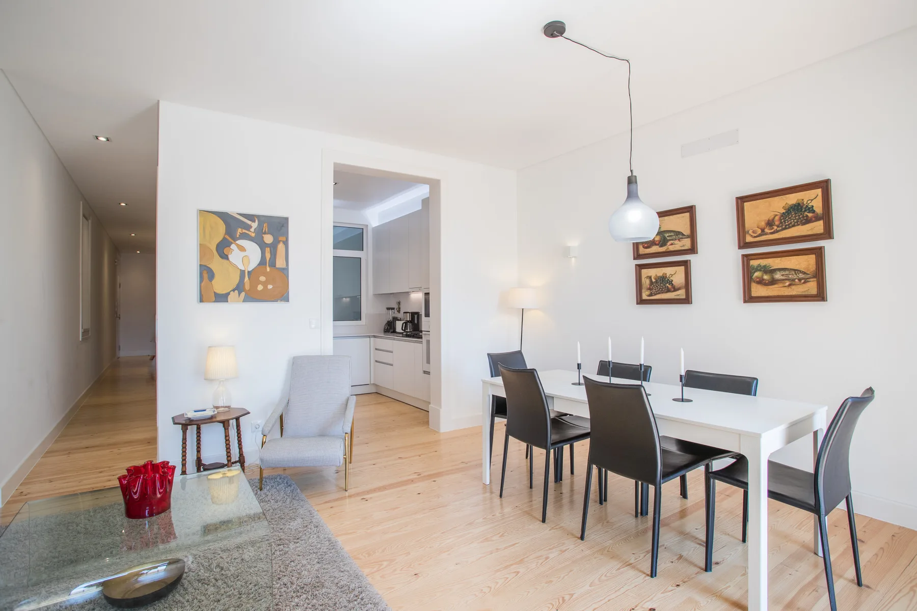 Luminoso comedor de apartamento con mesa, asientos y cocina abierta.