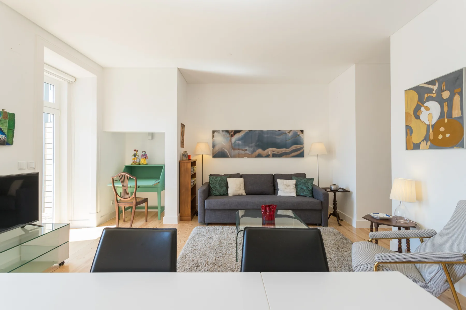 Una sala luminosa con asientos, una mesa de centro y arte colorido en las paredes.