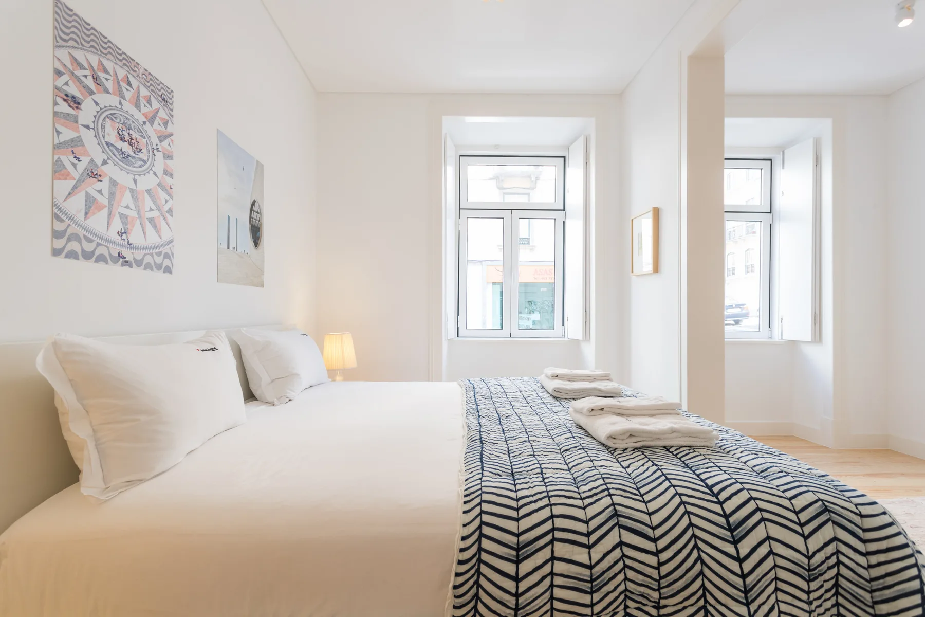 Un dormitorio luminoso con una cama tendida y ventanas grandes.