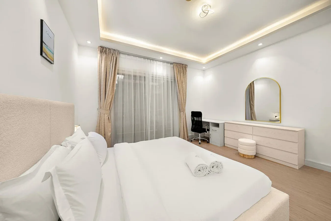 Un dormitorio luminoso con una cama bien arreglada y una ventana con cortinas.