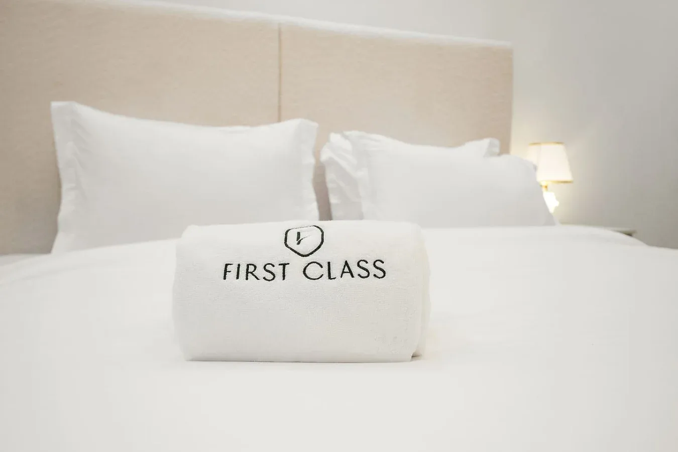 Una cama bien tendida con almohadas blancas y una toalla doblada encima.