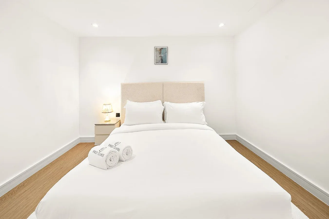 Un dormitorio luminoso con una cama bien tendida y una pequeña mesita de noche.