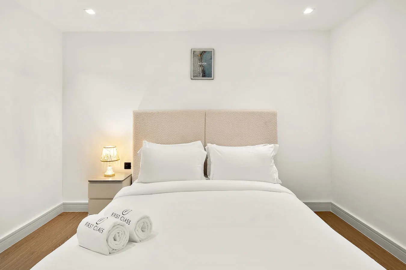 Un dormitorio luminoso con una cama bien tendida y una lámpara de noche.