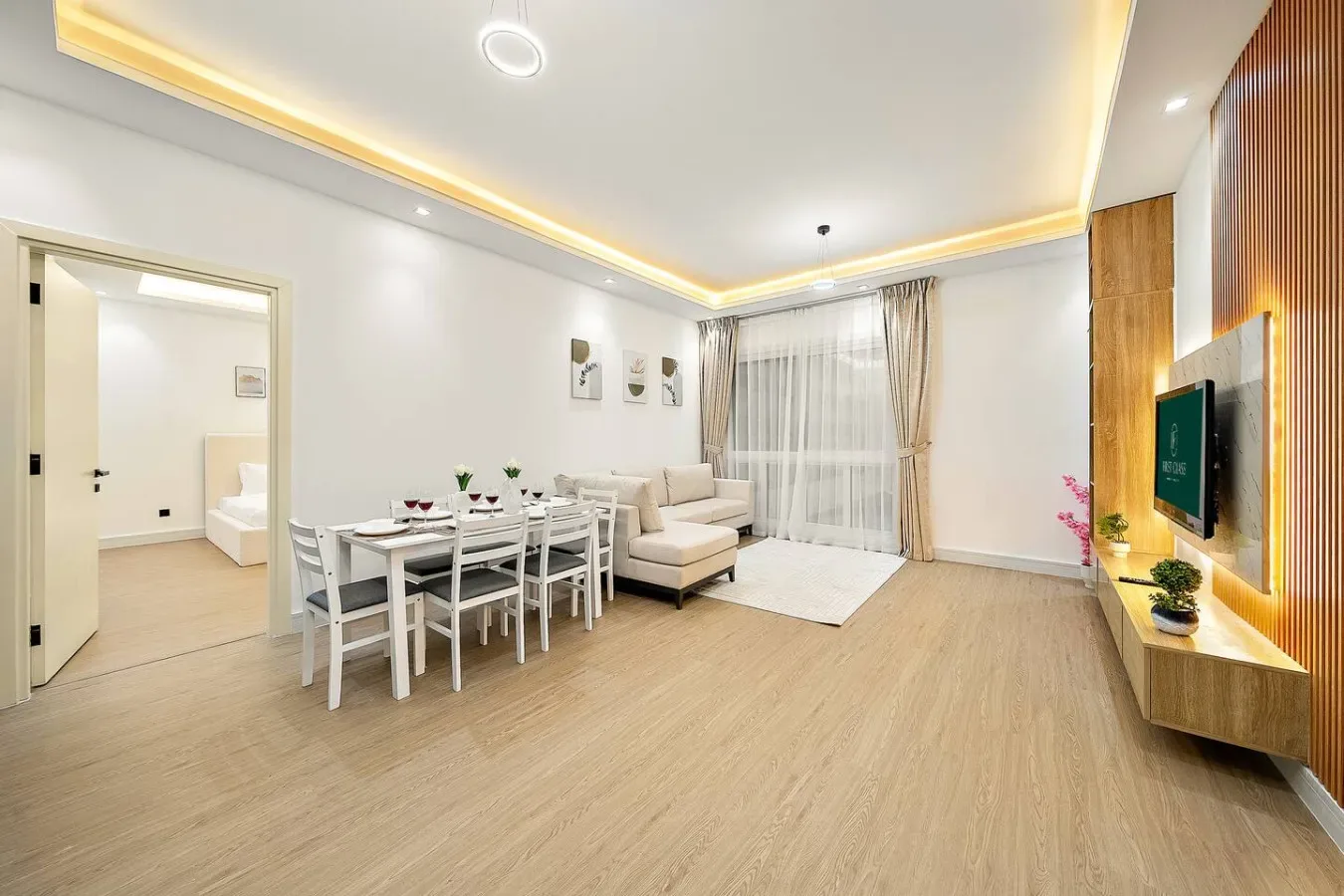 Una luminosa sala de estar y comedor con asientos junto a grandes ventanas con cortinas.