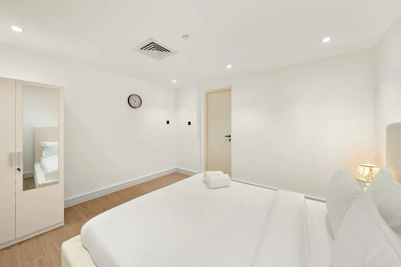 Un dormitorio luminoso con una cama grande y un armario con espejo.