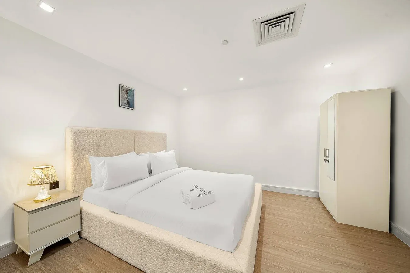 Un dormitorio luminoso con una cama bien tendida y un armario.