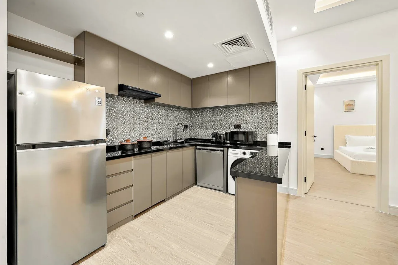 Una cocina moderna con electrodomésticos de acero inoxidable y una barra que da a un dormitorio.
