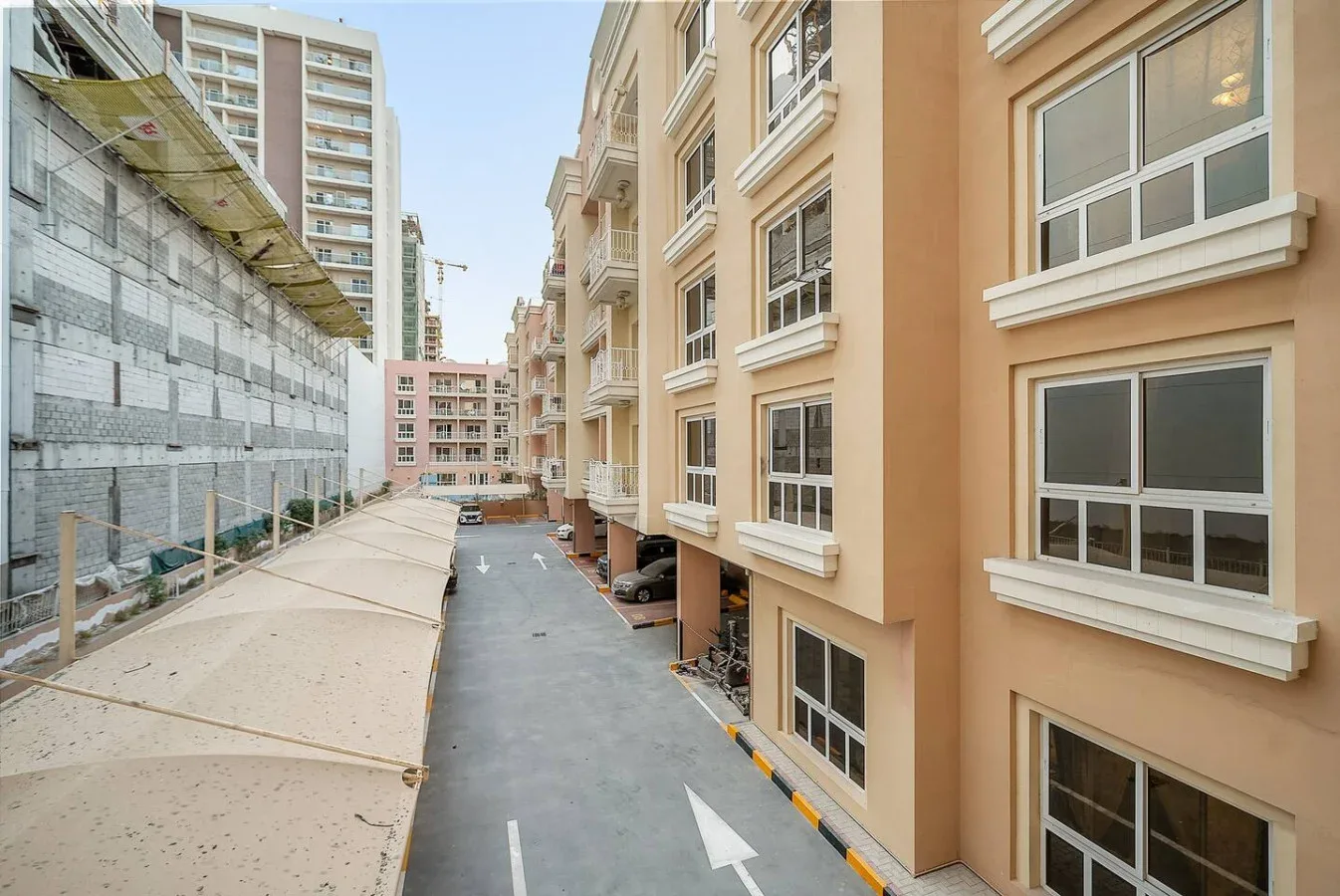 Un callejón pavimentado pasa entre edificios de apartamentos y una obra en construcción.