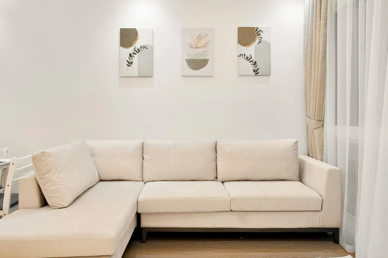 A bright living room with a beige sectional sofa and framed wall art.