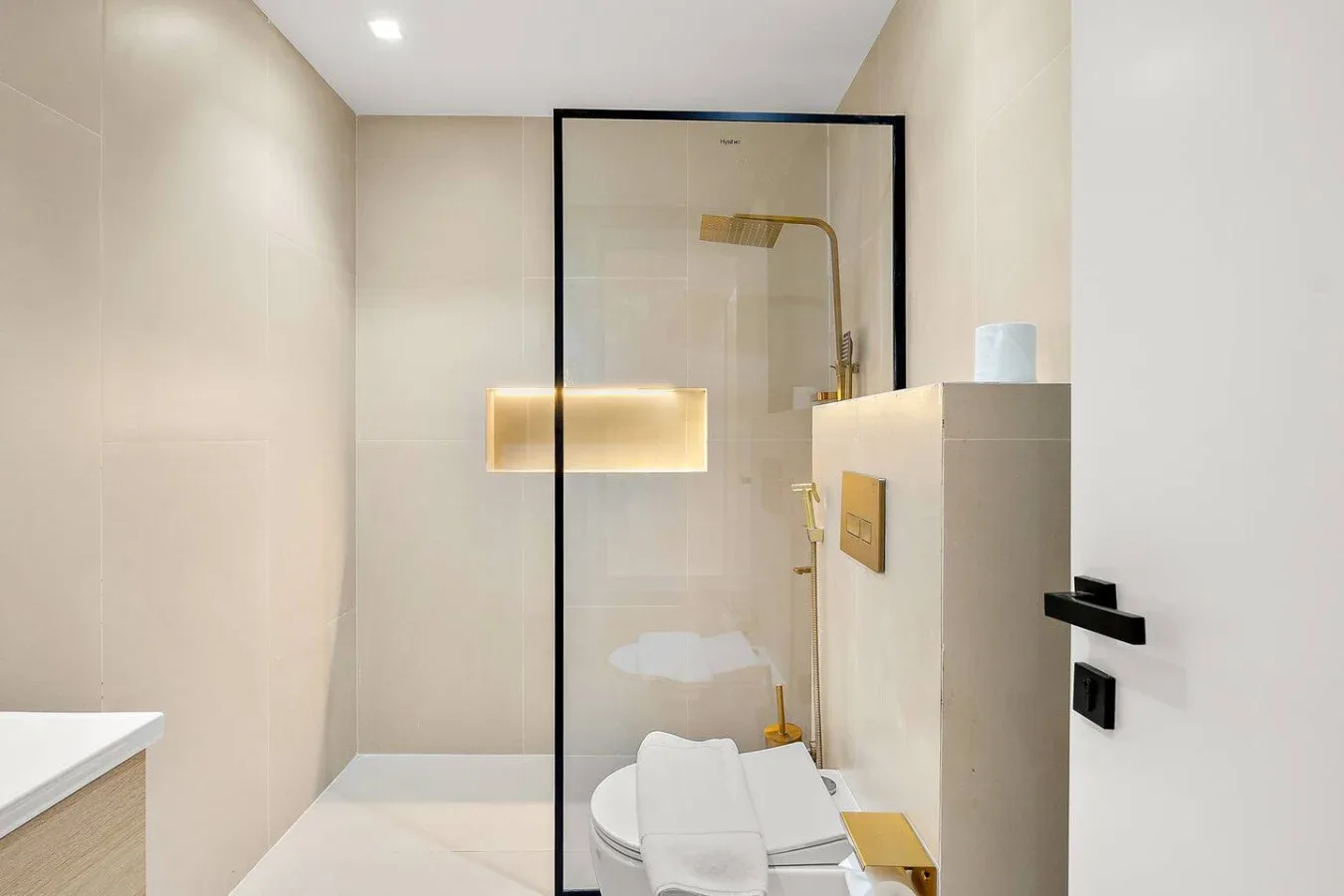 Un baño luminoso con una ducha de vidrio y toallas dobladas.