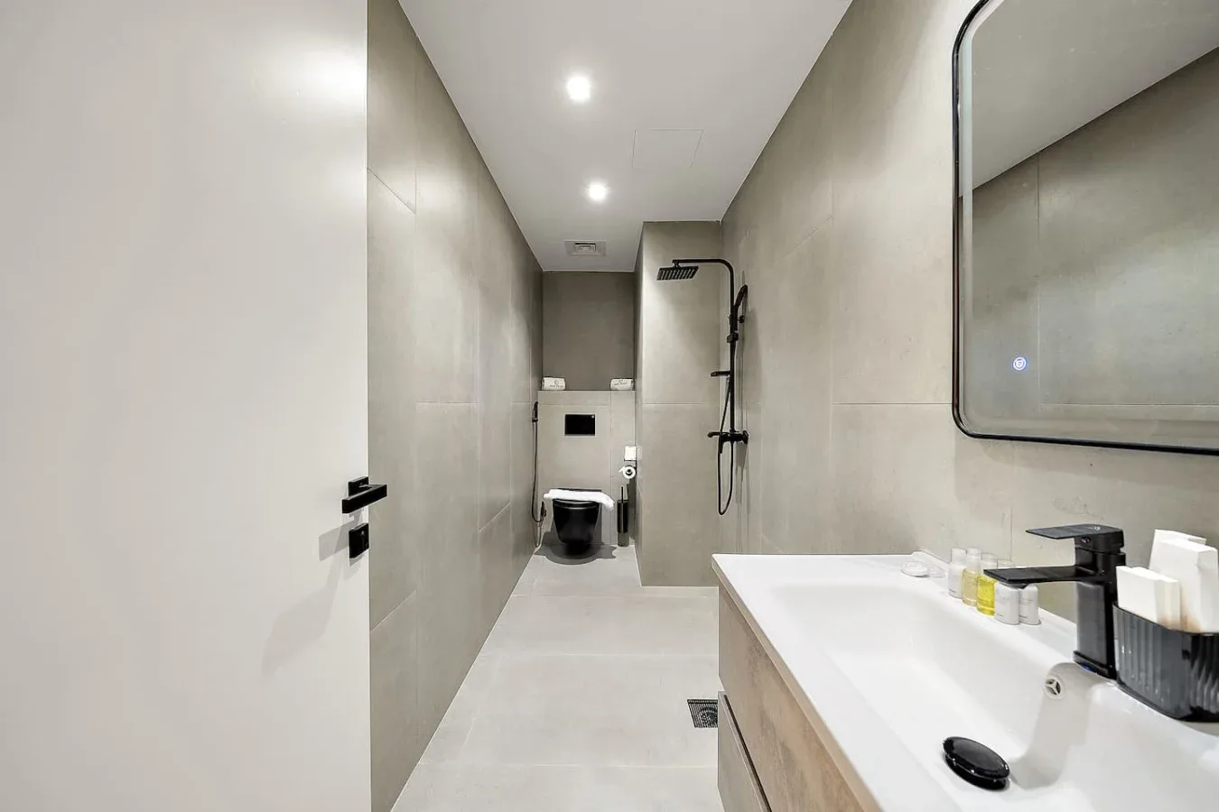Un baño moderno con inodoro suspendido, ducha y lavabo.