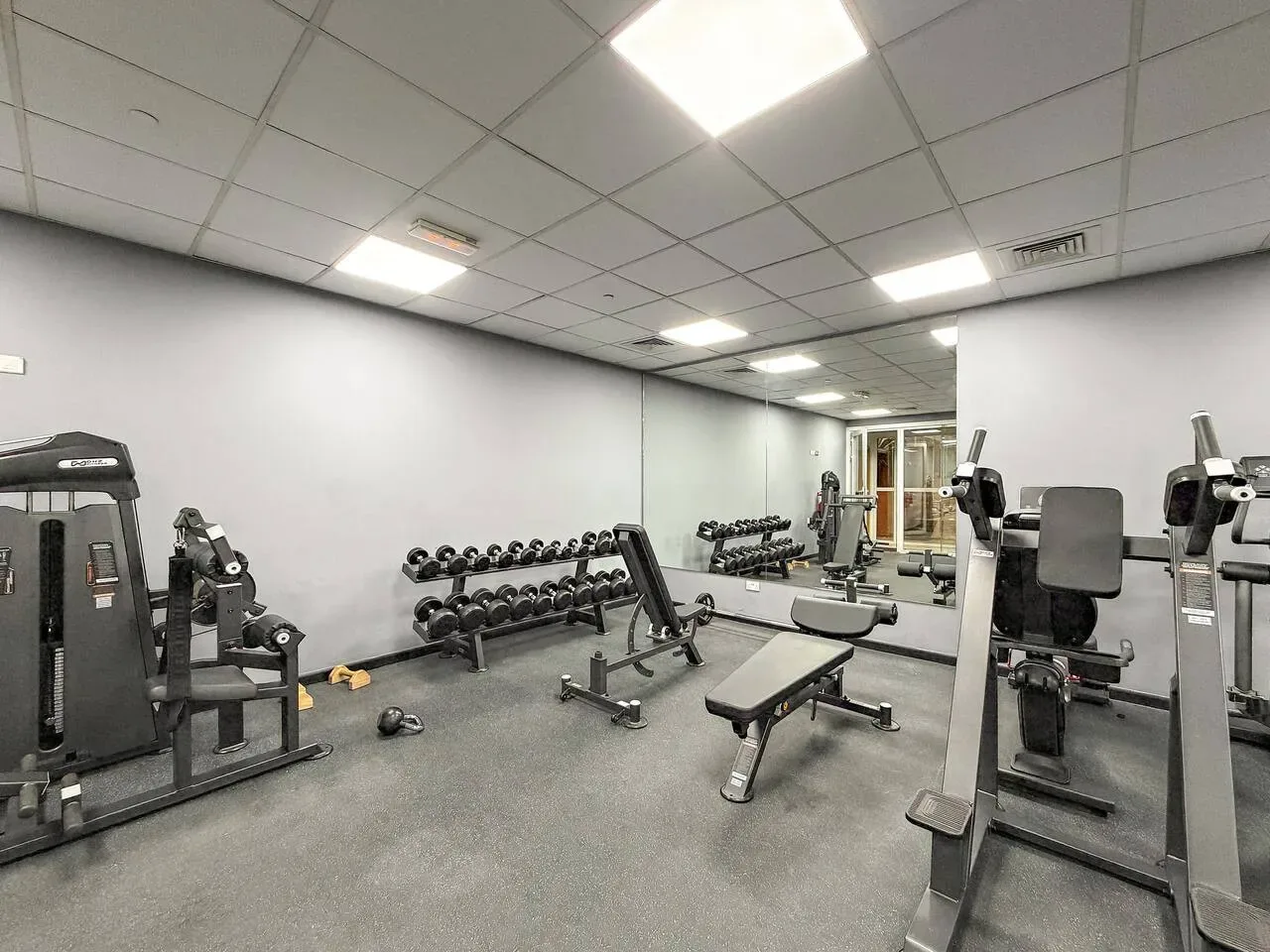 A gym with weight machines, dumbbells, and a workout bench.