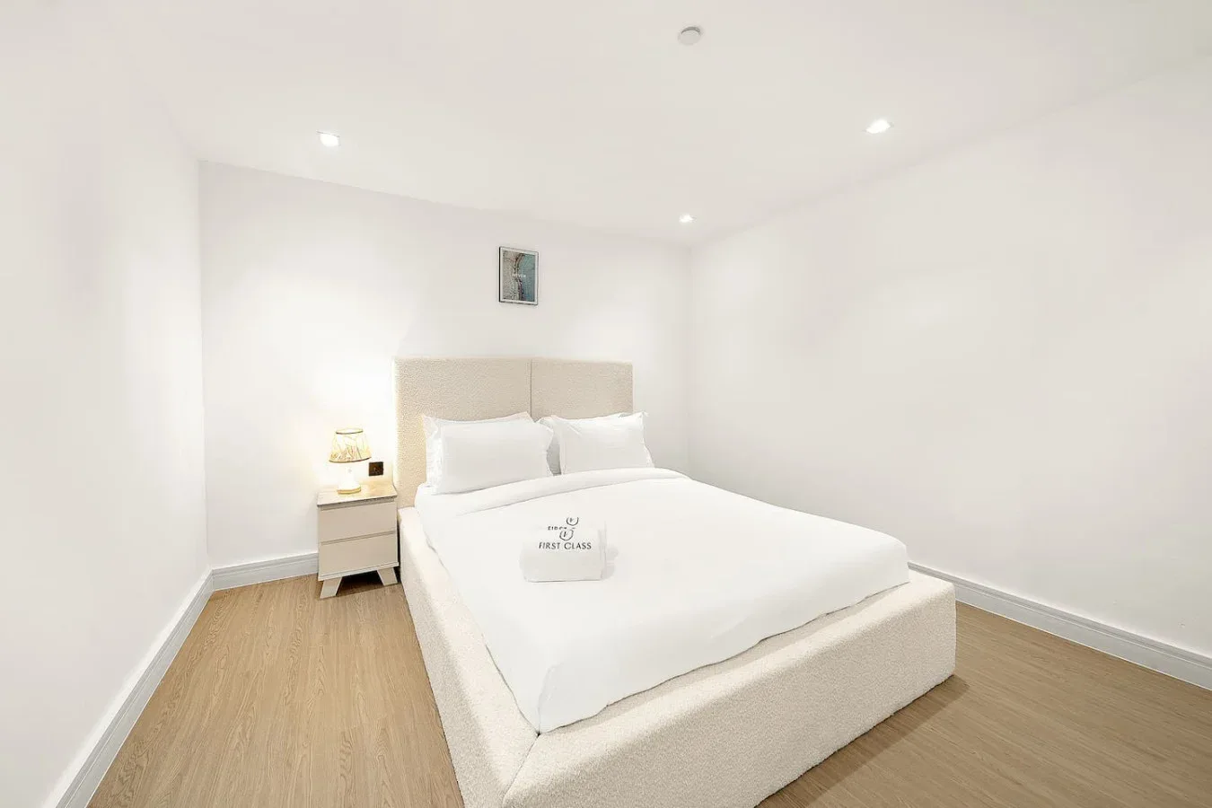 Un dormitorio luminoso con una cama bien tendida y una mesita de noche.