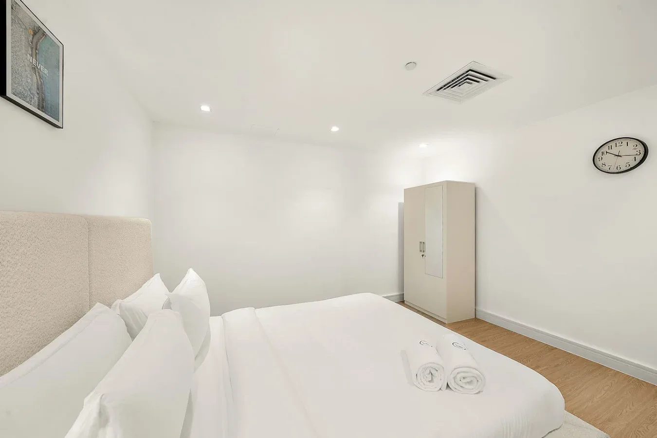 Un dormitorio luminoso con una cama bien tendida y toallas dobladas.