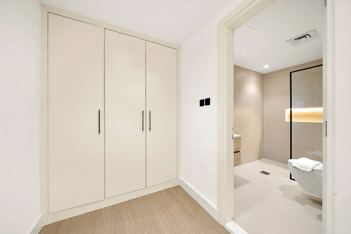 Una zona de dormitorio luminosa con armario empotrado da a un baño.