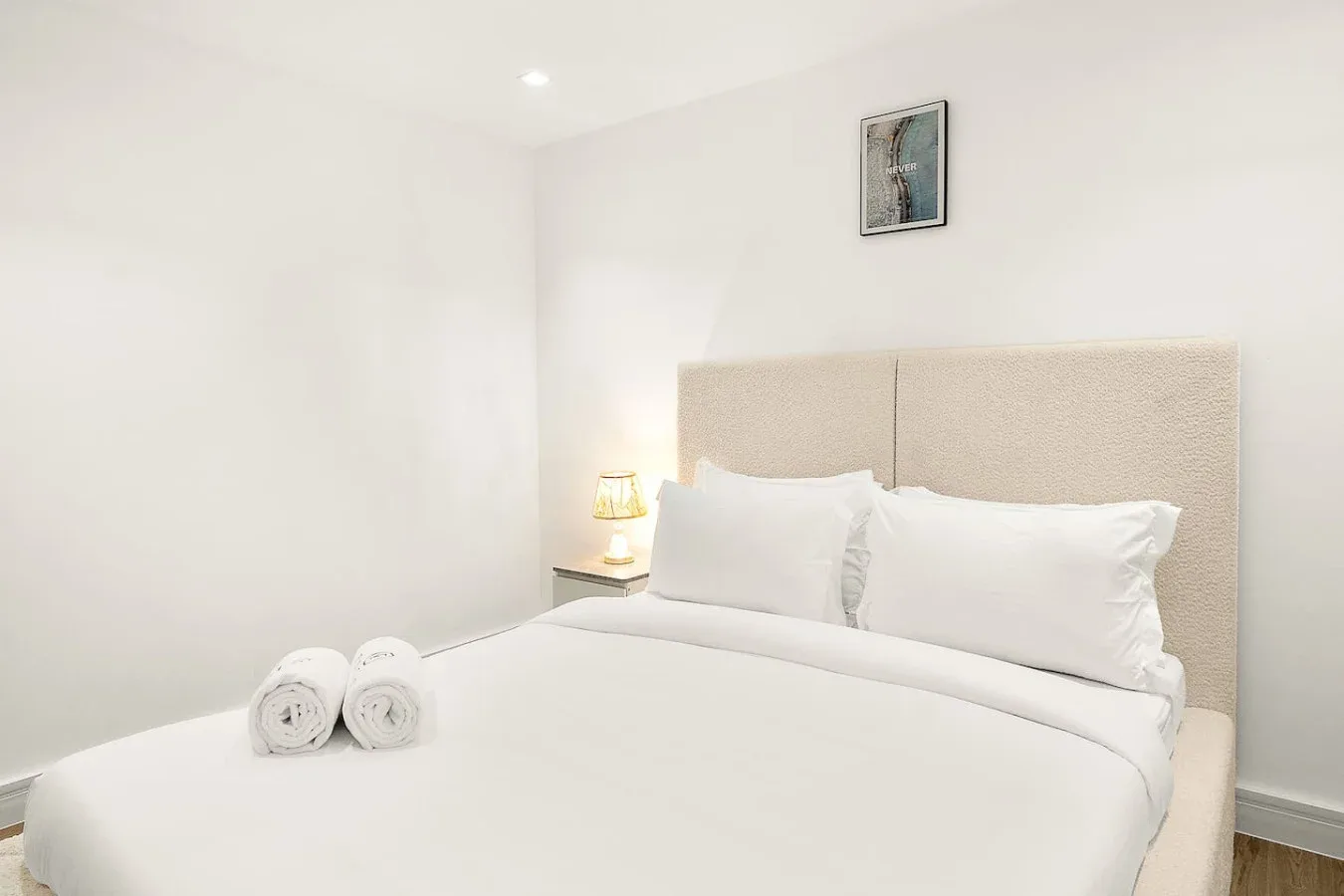 Un dormitorio luminoso con una cama bien hecha y una pequeña lámpara de noche.