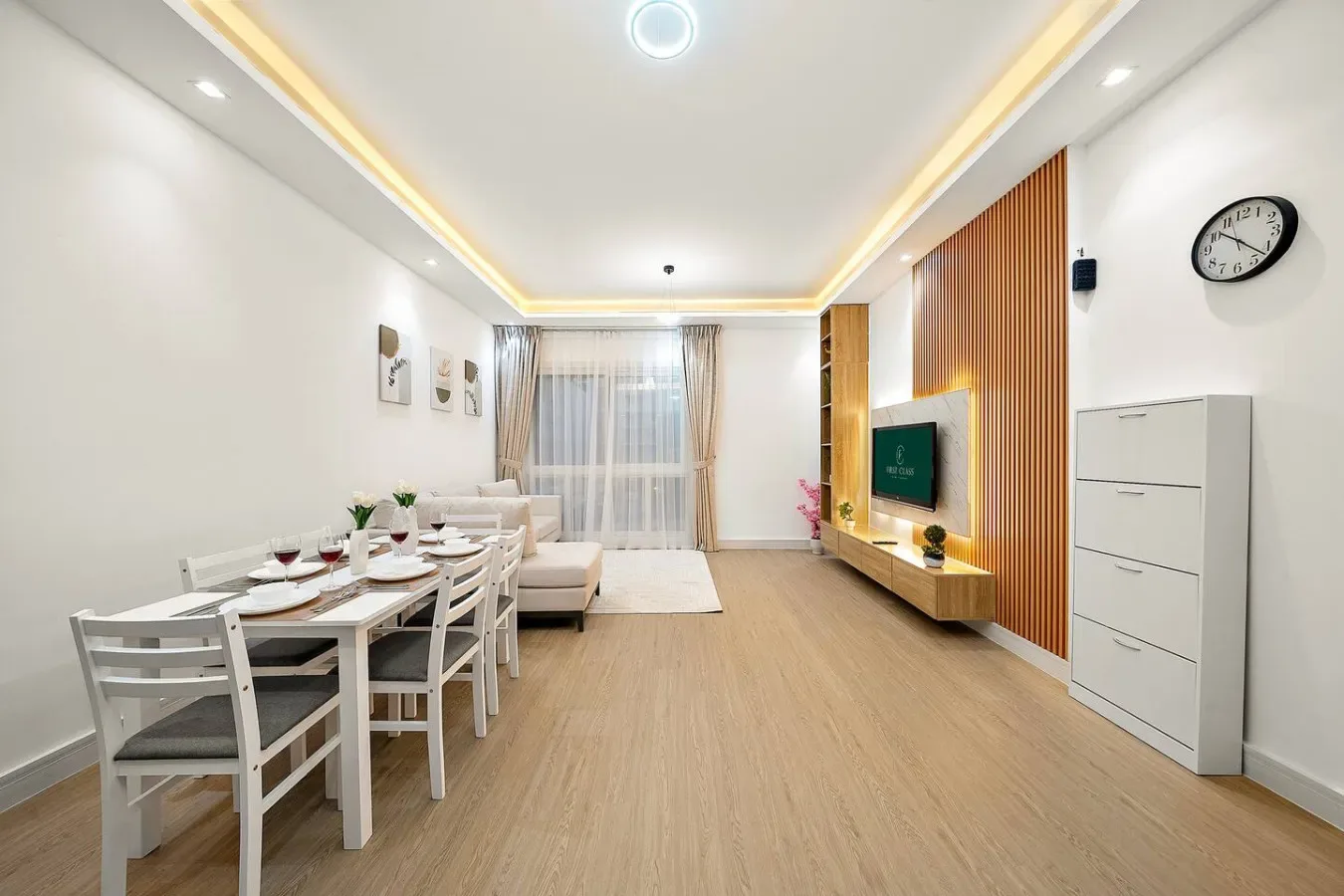 Un luminoso comedor y sala de estar con una mesa, asientos y un televisor en la pared.