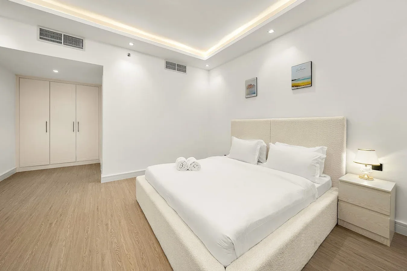 Un dormitorio luminoso con una cama grande, una mesita de noche y un armario empotrado.