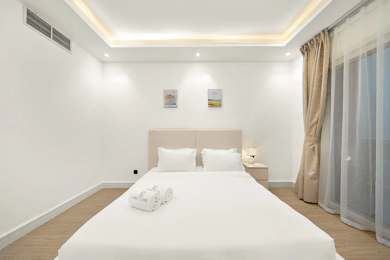 Un dormitorio luminoso con una cama bien hecha y cortinas junto a la ventana.