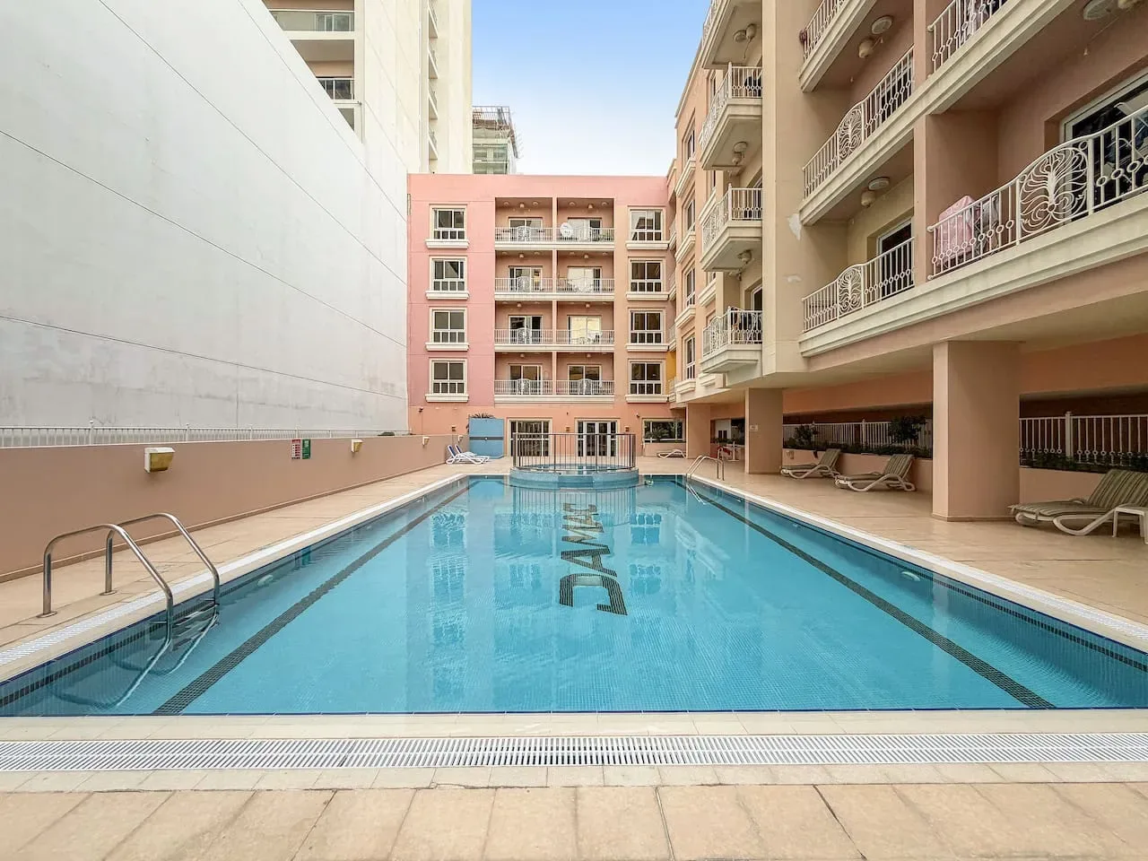 Una piscina está entre edificios de varias plantas, con balcones que dan al agua.