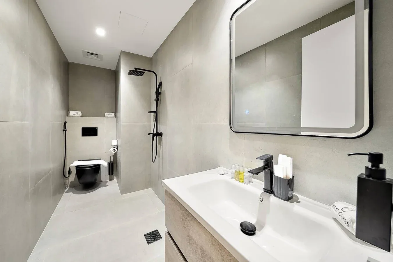 Un baño moderno con un lavabo alargado, un espejo grande y una ducha.