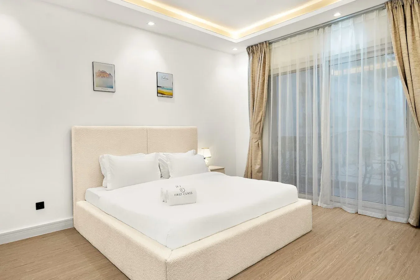 Un dormitorio luminoso con una cama grande junto a ventanas altas con cortinas.
