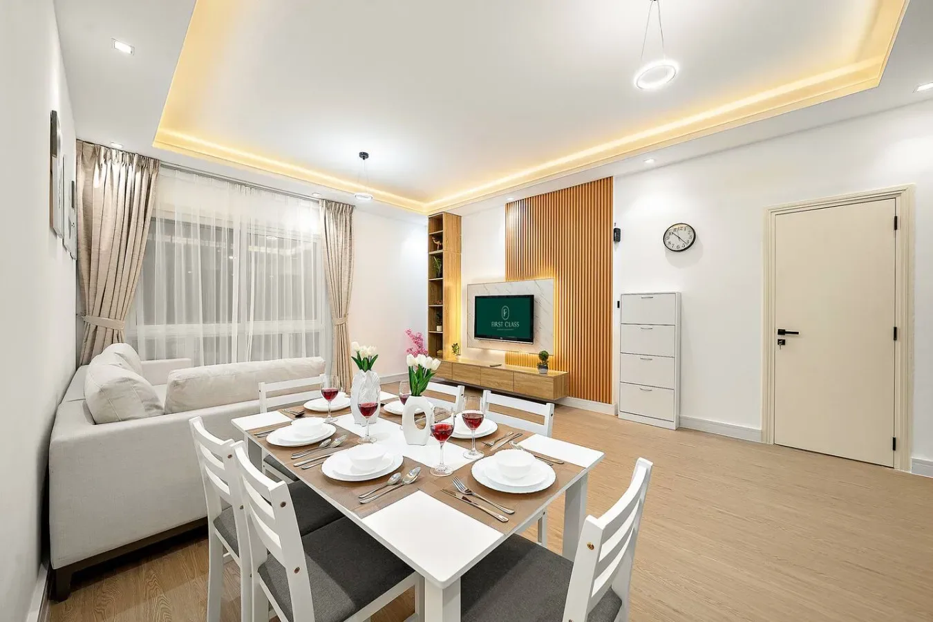 A bright living and dining area with a table set beside a sofa and television.