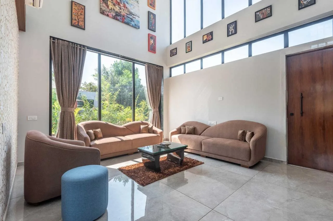 Una sala luminosa con asientos alrededor de una mesa de centro de vidrio y ventanas altas.