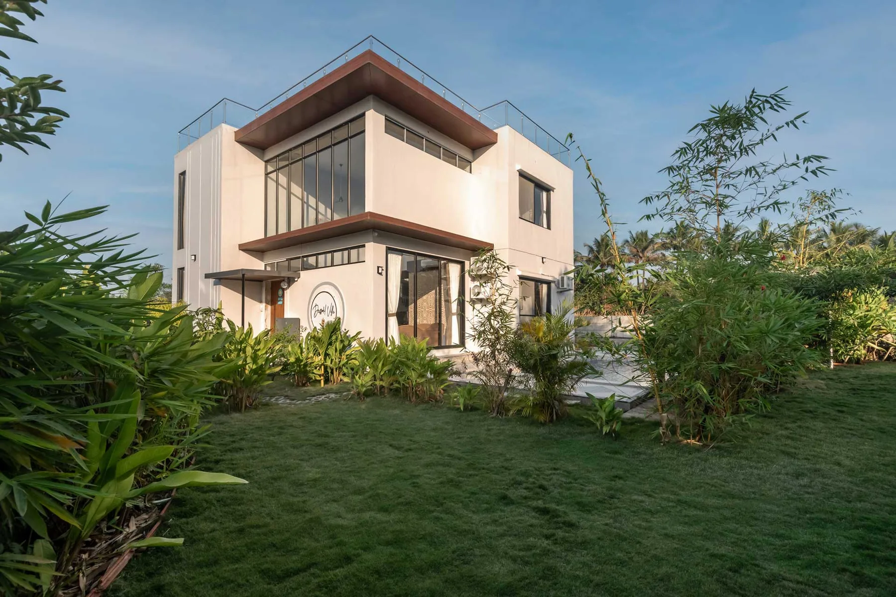 Una casa moderna se alza tras un jardín paisajístico con césped verde.