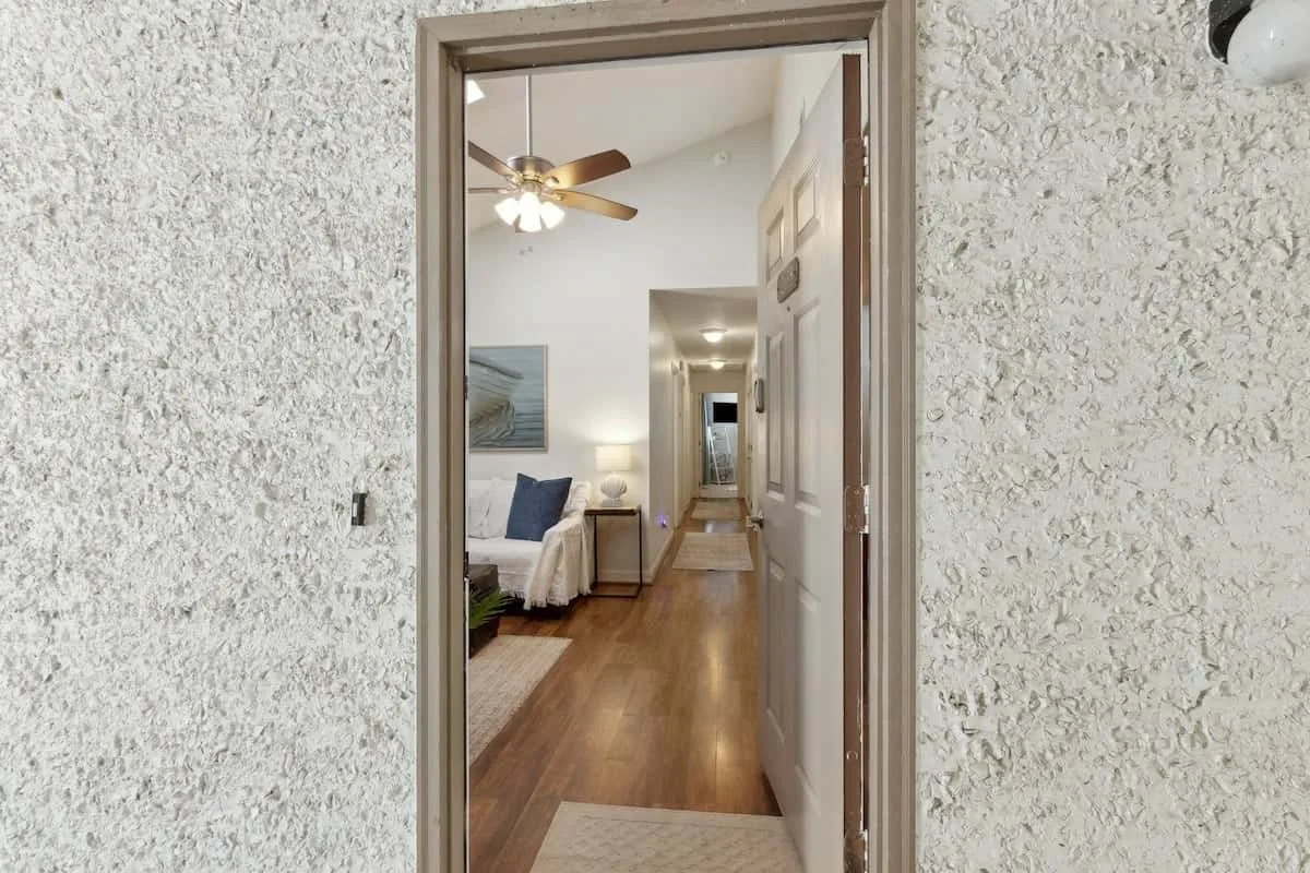 A hallway leads past a small seating area beneath a ceiling fan.