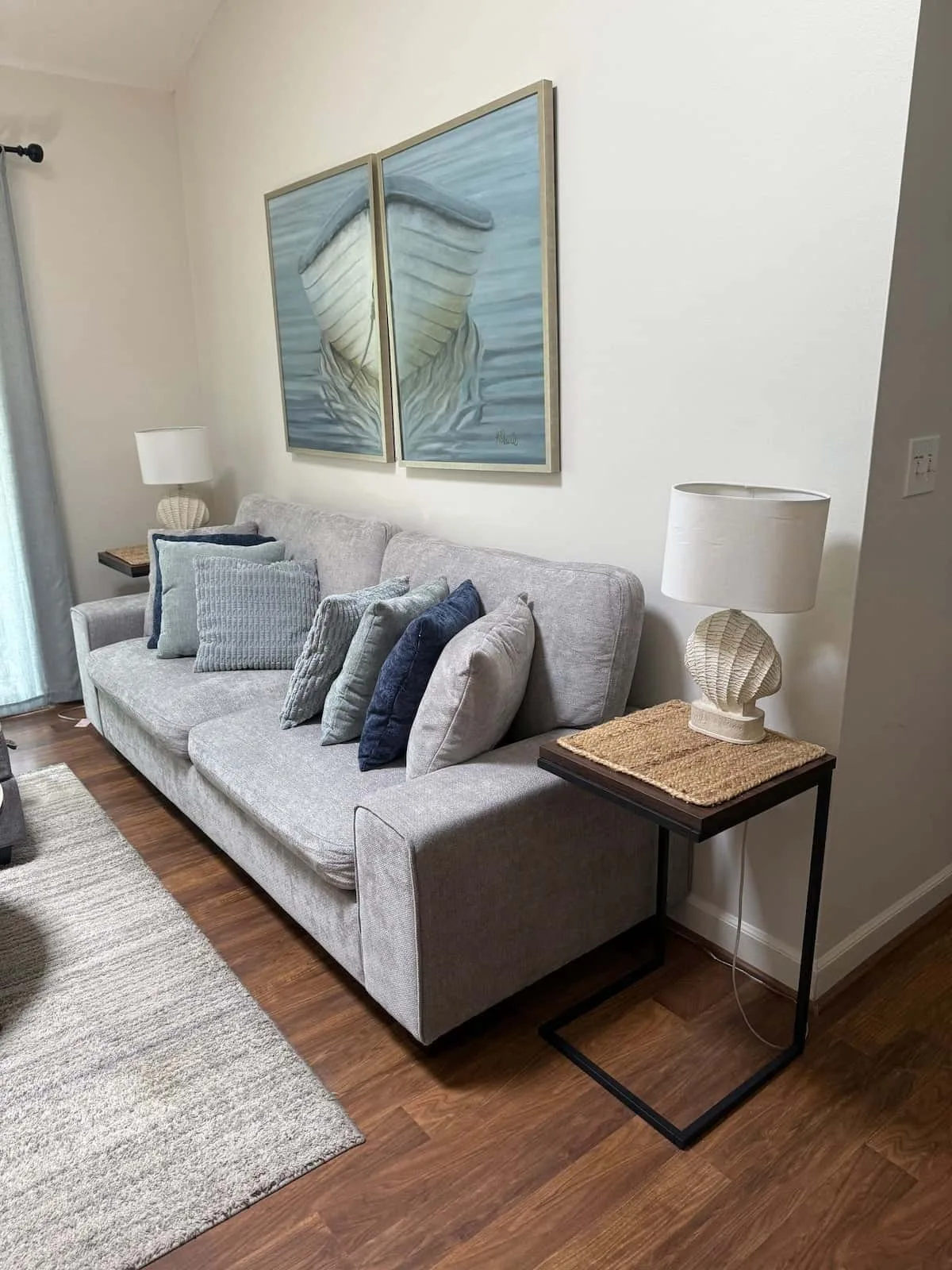 A living room with a gray sofa beneath two blue-toned framed artworks.