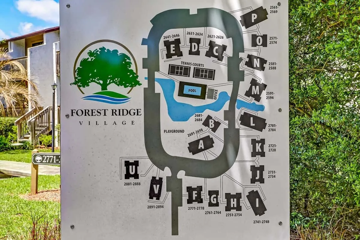 A community directory sign displays a site map beside a landscaped path.