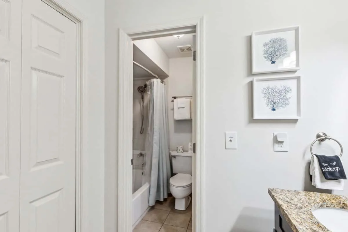 A bathroom with a shower, toilet, and stone-look vanity countertop.
