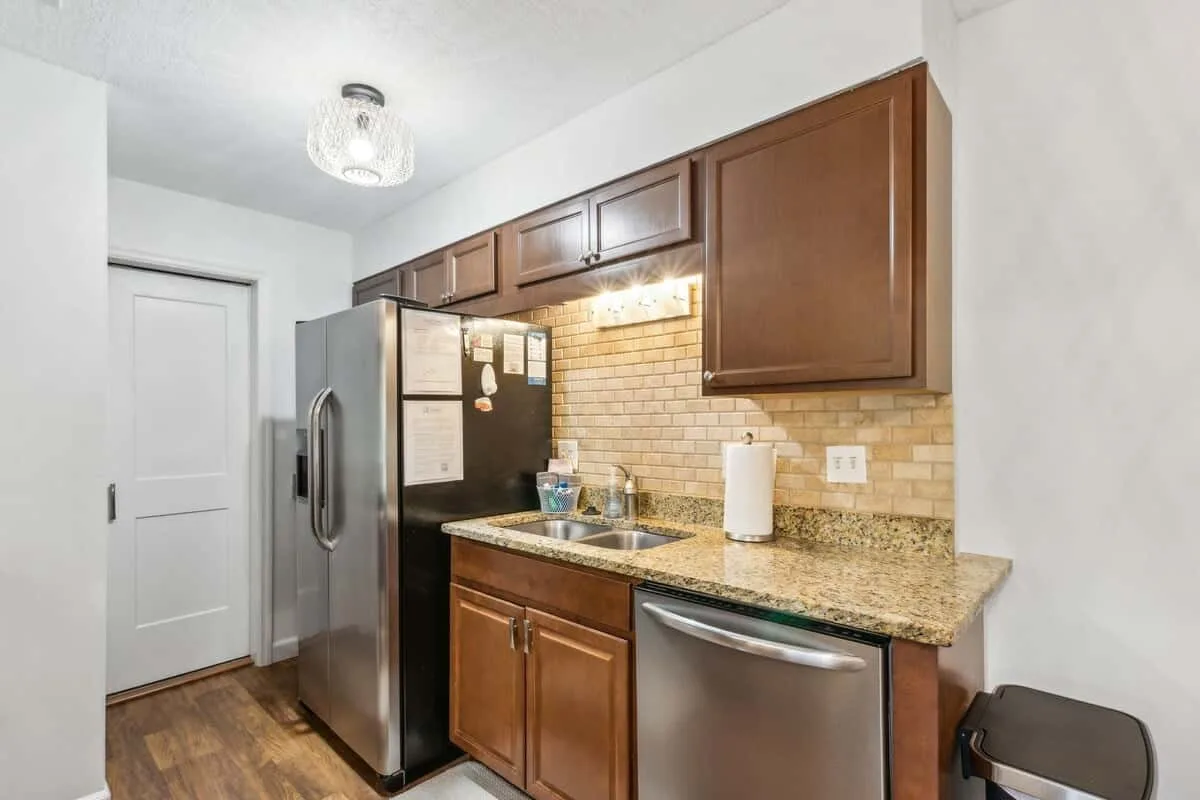 A compact kitchen with dark wood cabinets, a refrigerator, and a countertop.