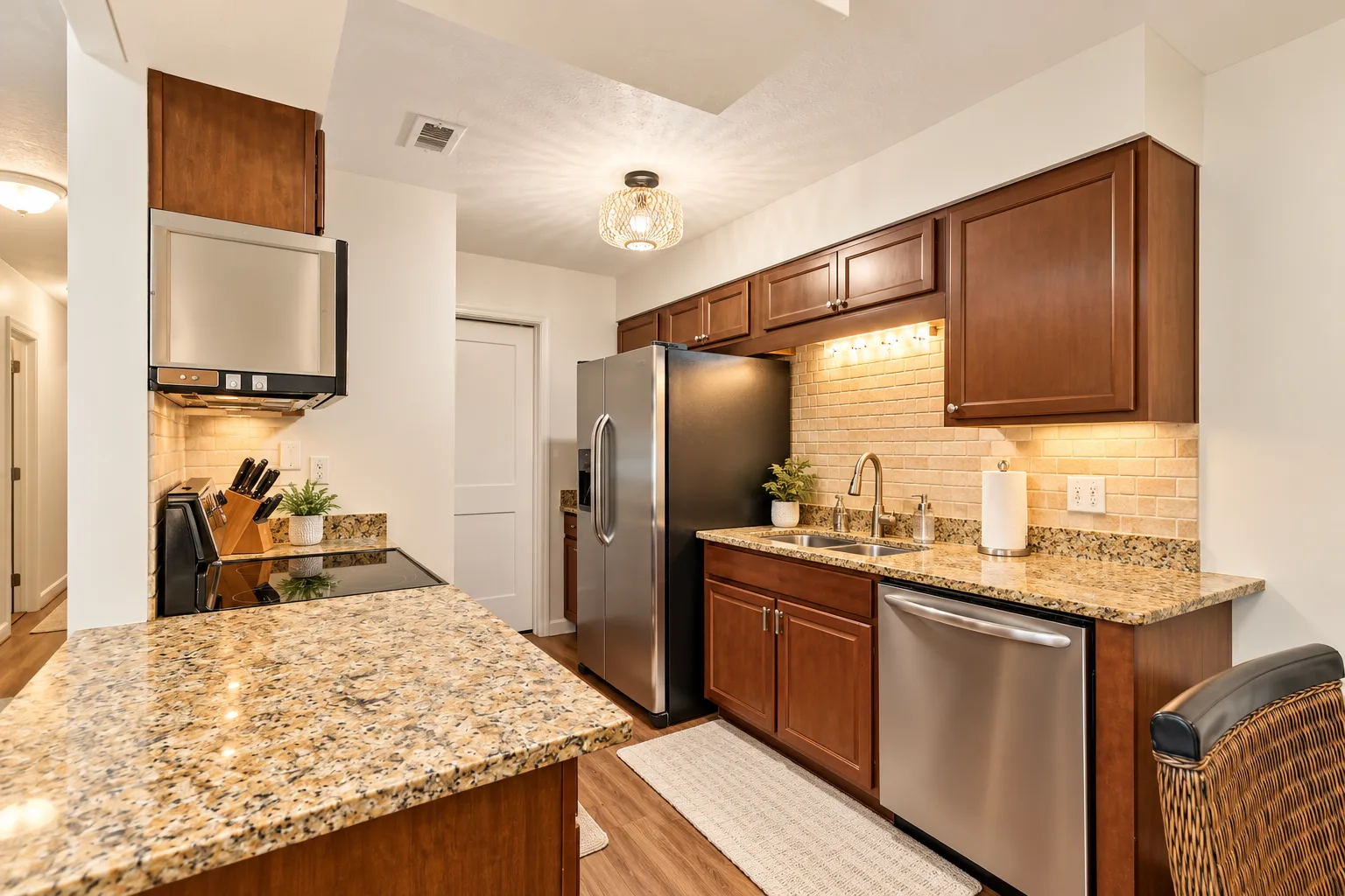 A kitchen with wooden cabinets, stone countertops, and stainless steel appliances.