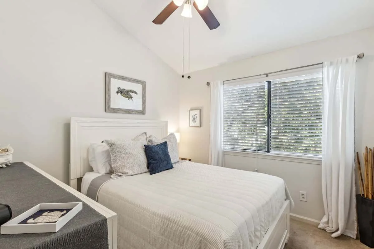 A bedroom with a neatly made bed beside a wide window.