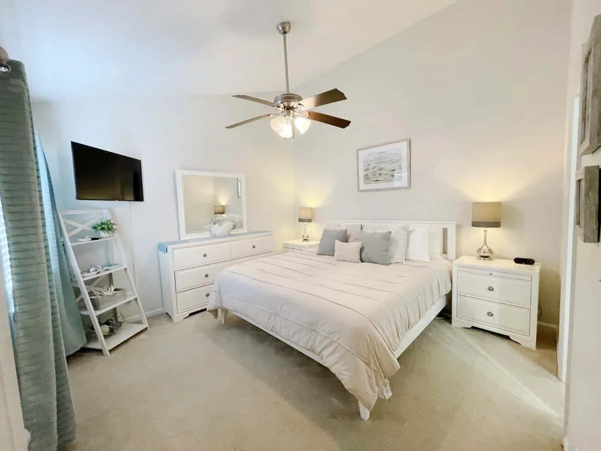 A bright bedroom with a neatly made bed and matching bedside tables.
