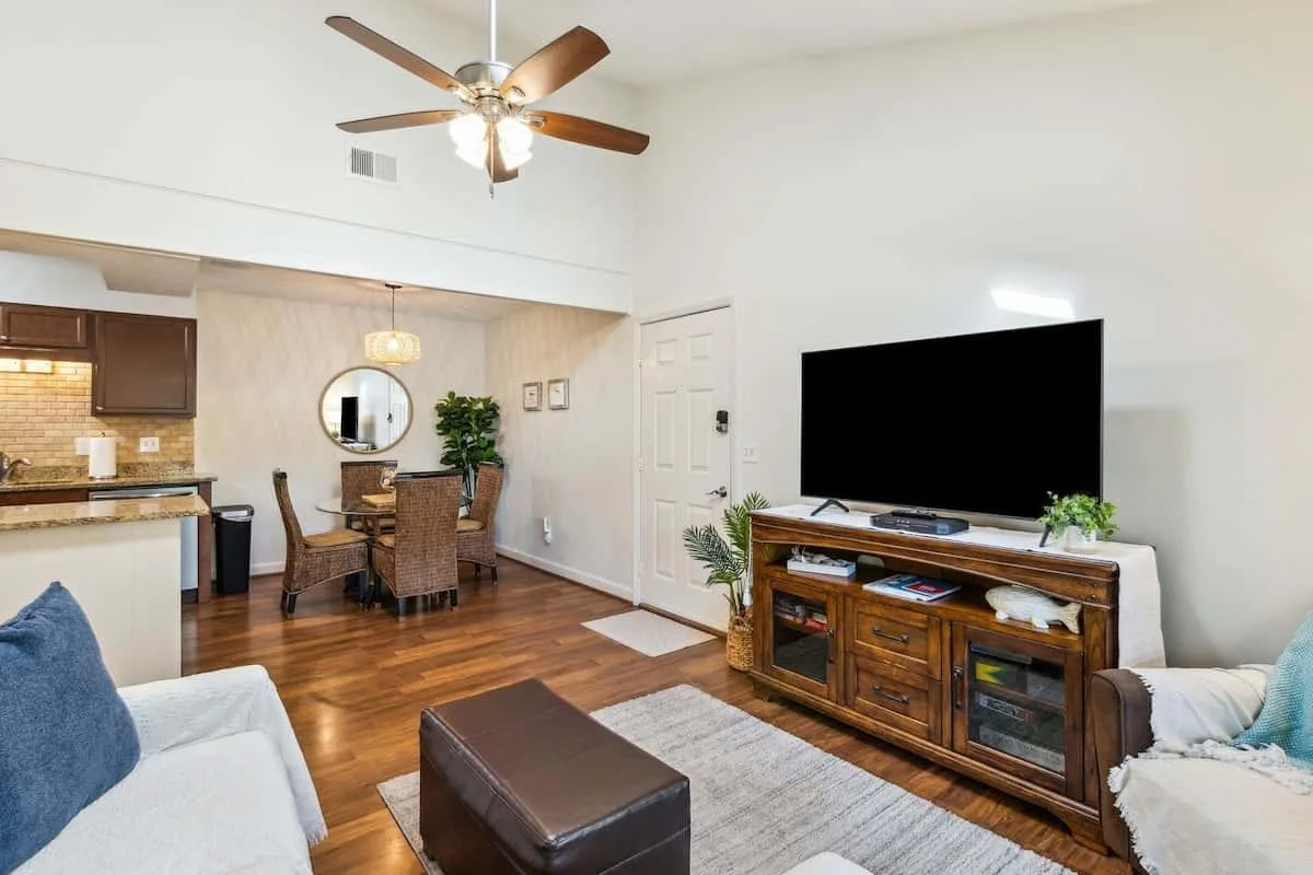 A living room with a television, wooden media console, and dining area.