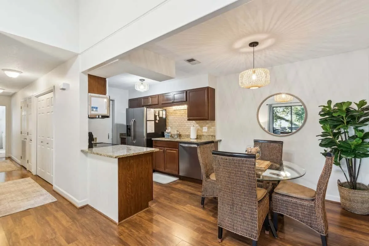 An open kitchen and dining area with a round table and woven seating.