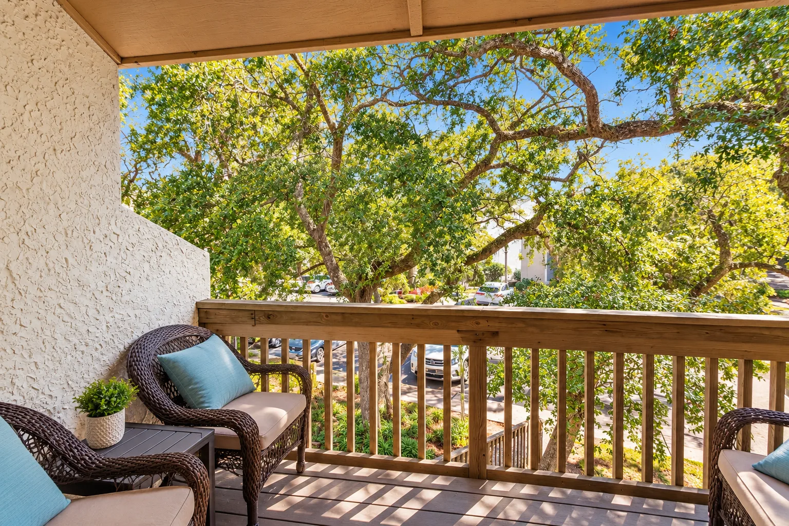 A covered balcony with seating overlooks leafy trees and a wooden railing.