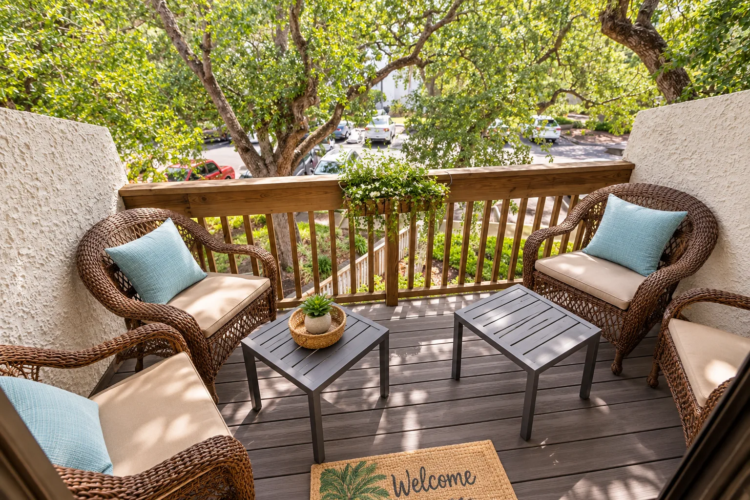 A balcony seating area with cushioned chairs and small tables beneath leafy trees.