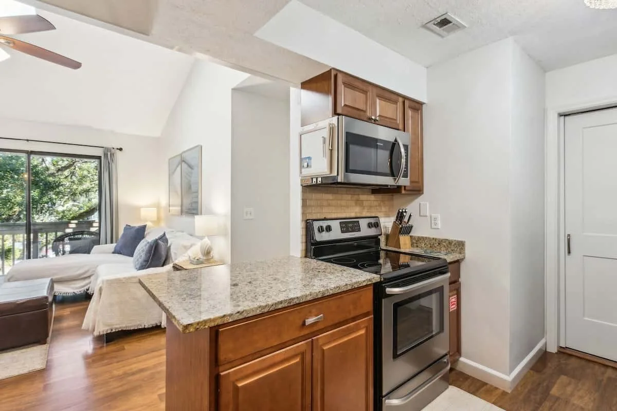 An open-plan kitchen with a breakfast counter and a living area by the windows.