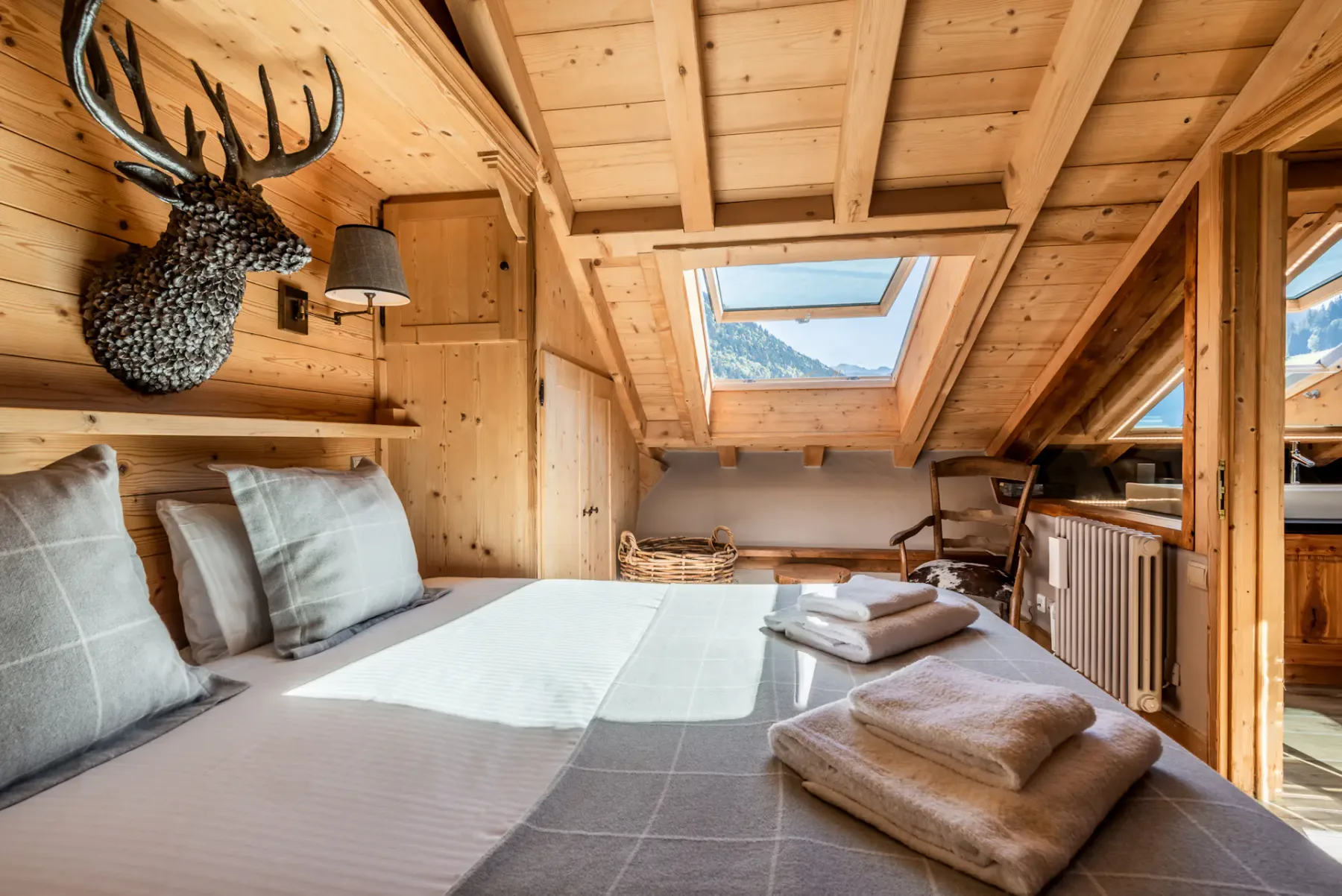 A wood-paneled bedroom with a bed beneath a sloped ceiling and skylight.