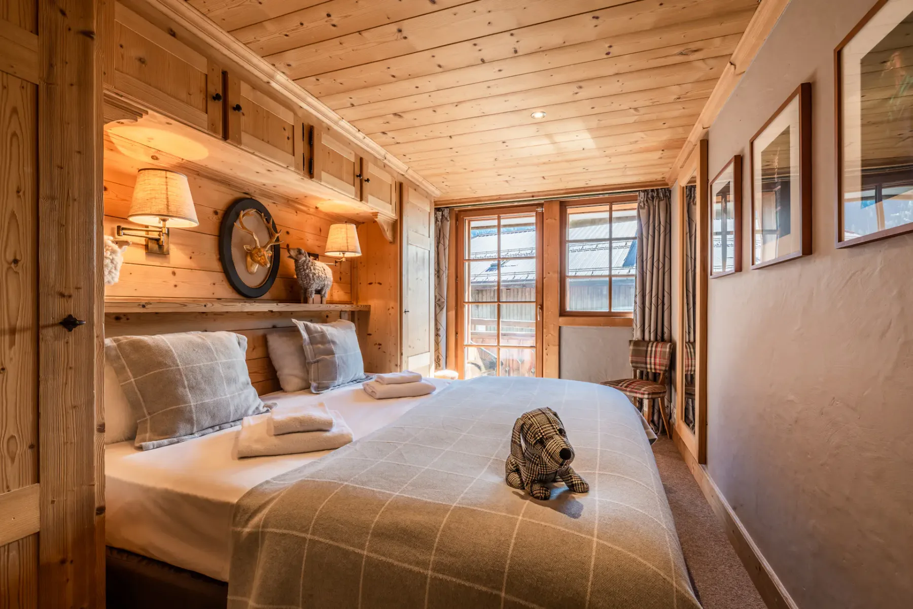 A wood-paneled bedroom with a double bed and windows at the far end.