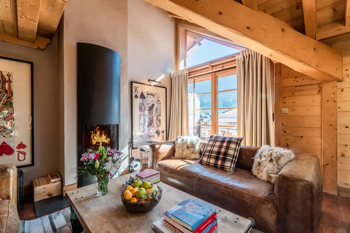 A living room with a brown sofa, a large window, and a fireplace.