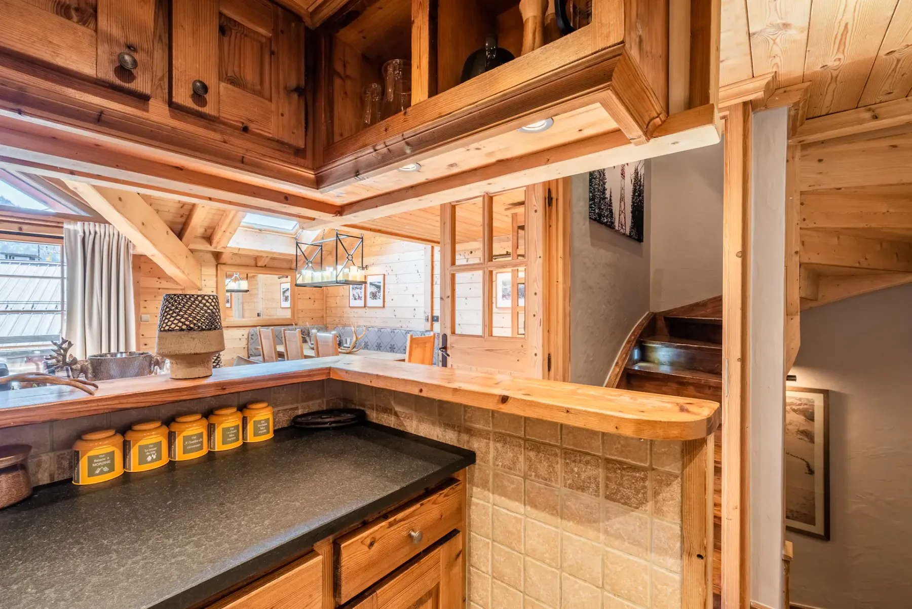 A wood-paneled kitchen opens onto a dining area with a table and chairs.